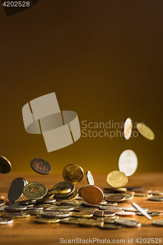 Image of The silver and golden coins and falling coins on wooden background