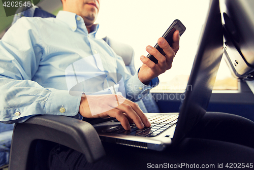 Image of man with smartphone and laptop in travel bus