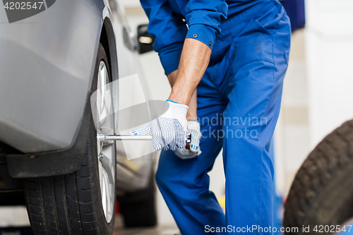 Image of mechanic with screwdriver changing car tire