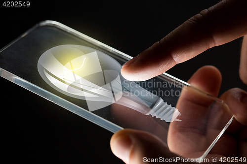 Image of close up of hands with lightbulb smartphone