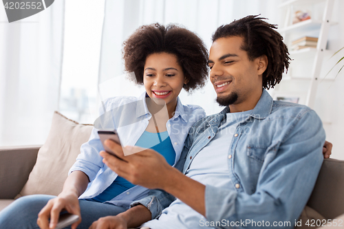 Image of happy couple with smartphones at home