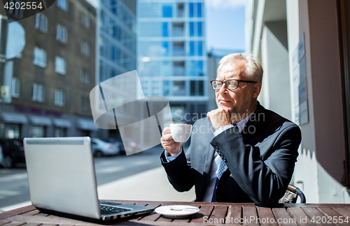 Image of senior businessman with laptop drinking coffee