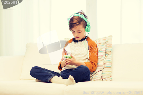 Image of boy with smartphone and headphones at home