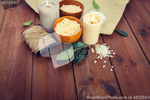 Image of close up of natural body scrub and candles on wood