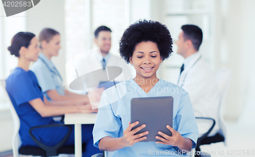 Image of happy doctor with tablet pc over team at clinic