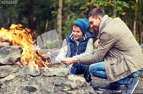 Image of father and son roasting marshmallow over campfire