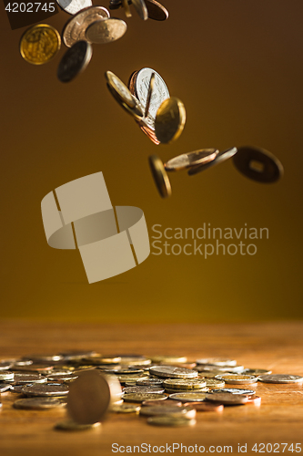 Image of The silver and golden coins and falling coins on wooden background
