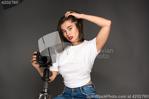 Image of Portrait of a young woman with camera on the gray background