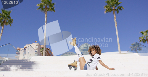 Image of Female wearing roller skates sitting on stairs