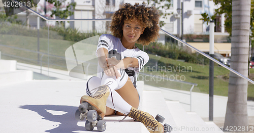 Image of Smiling female sitting on stairs wearing rollerskates