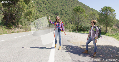 Image of Young travellers hitch hiking on road