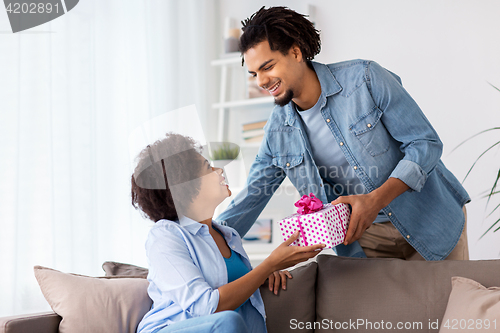 Image of happy couple with gift box at home