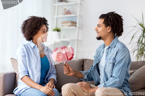 Image of happy couple with bunch of flowers at home