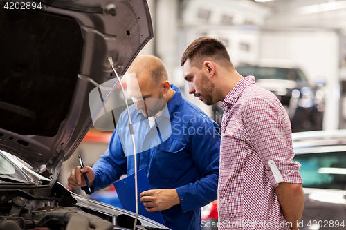 Image of auto mechanic with clipboard and man at car shop