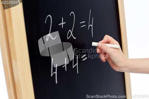 Image of hand with chalk writing numbers on blackboard