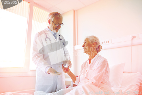 Image of doctor giving medicine to senior woman at hospital