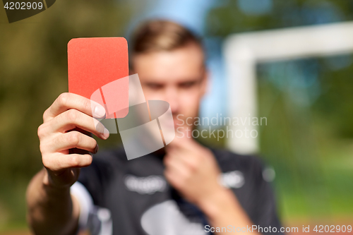 Image of referee hands with red card on football field