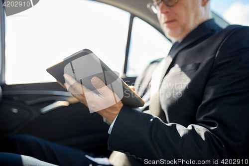 Image of senior businessman with tablet pc driving in car