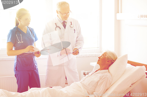 Image of doctor and nurse visiting senior woman at hospital