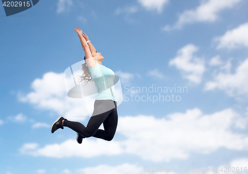 Image of happy sporty young woman jumping in blue sky