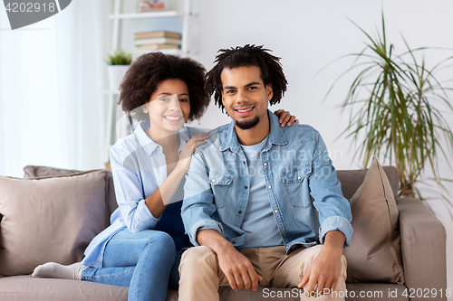 Image of happy couple sitting on sofa at home