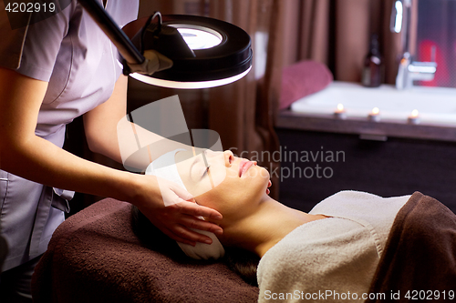 Image of beautician doing face massage to woman at spa