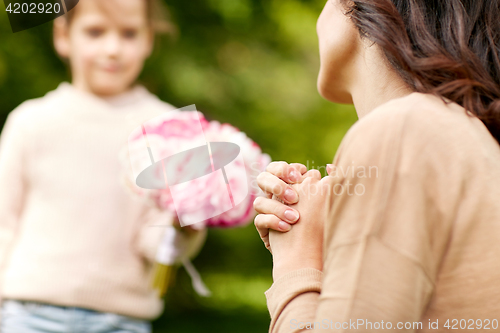 Image of happy woman and girl with flowers outdoors