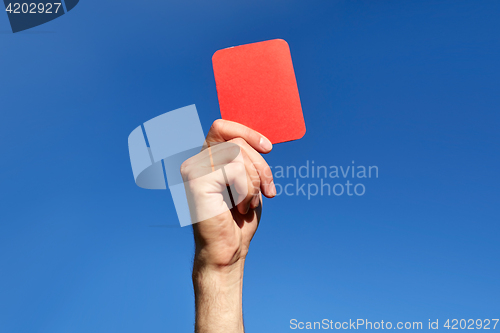 Image of referee hands with red card on football field