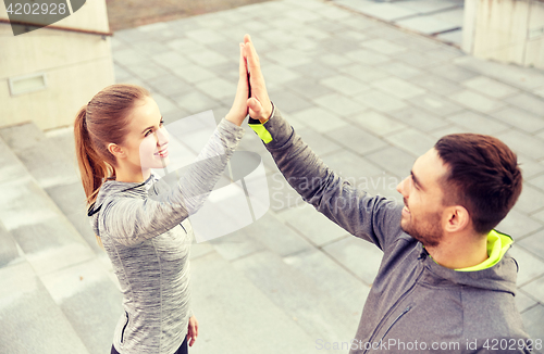 Image of smiling couple making high five on city street