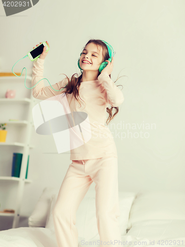 Image of girl jumping on bed with smartphone and headphones