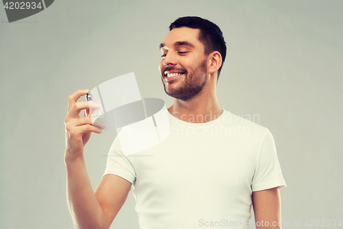 Image of smiling man with male perfume over gray background