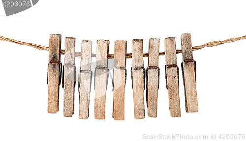 Image of Many old wooden clothespins on a rope isolated