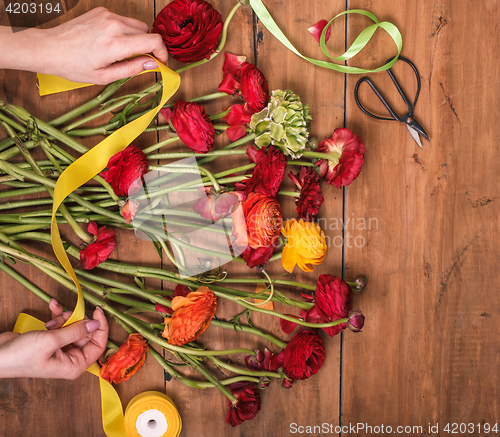 Image of Ranunkulyus bouquet of red flowers on a wooden background