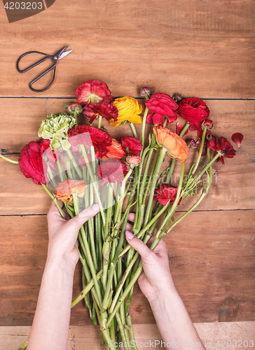 Image of Ranunkulyus bouquet of red flowers on a wooden background