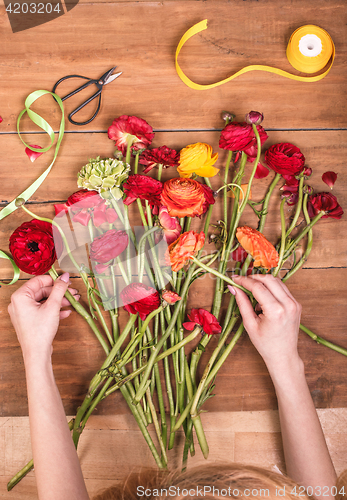 Image of Ranunkulyus bouquet of red flowers on a wooden background