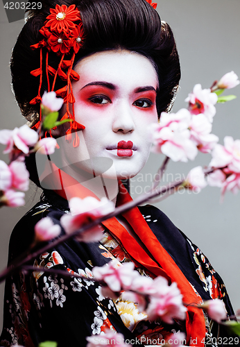 Image of young pretty geisha in black kimono among sakura, asian ethno 