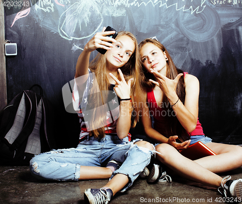 Image of back to school after summer vacations, two teen real girls in classroom with blackboard painted together, lifestyle people concept