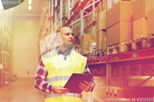 Image of man with clipboard in safety vest at warehouse