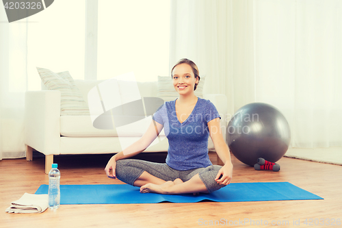 Image of woman making yoga in lotus pose on mat