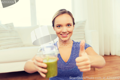 Image of happy woman with cup of smoothie showing thumbs up