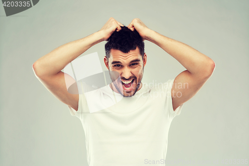 Image of crazy shouting man in t-shirt over gray background