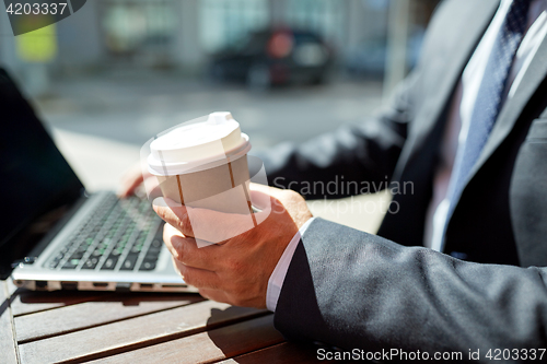 Image of senior businessman with laptop and coffee outdoors