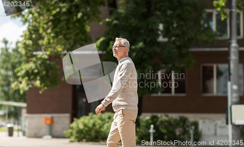 Image of senior man walking along summer city street