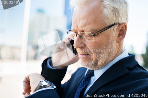 Image of senior businessman calling on smartphone in city