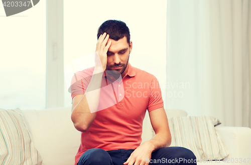 Image of unhappy man suffering from headache at home