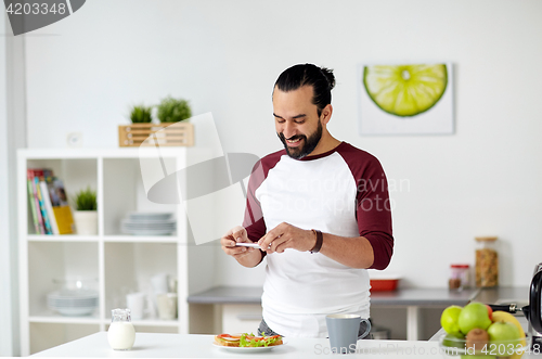 Image of man photographing food by smartphone at home