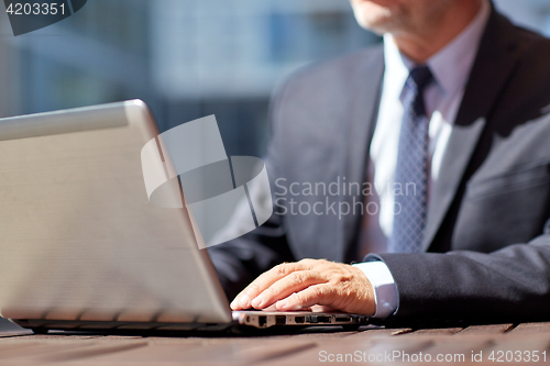 Image of senior businessman with laptop at outdoor cafe