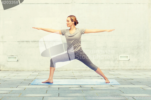 Image of woman making yoga warrior pose on mat