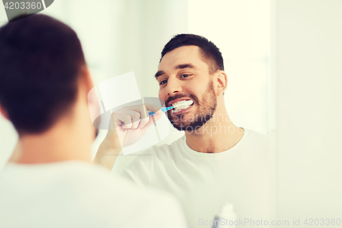 Image of man with toothbrush cleaning teeth at bathroom