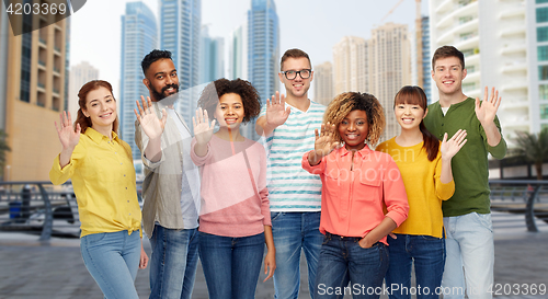 Image of international group of people waving hand in city